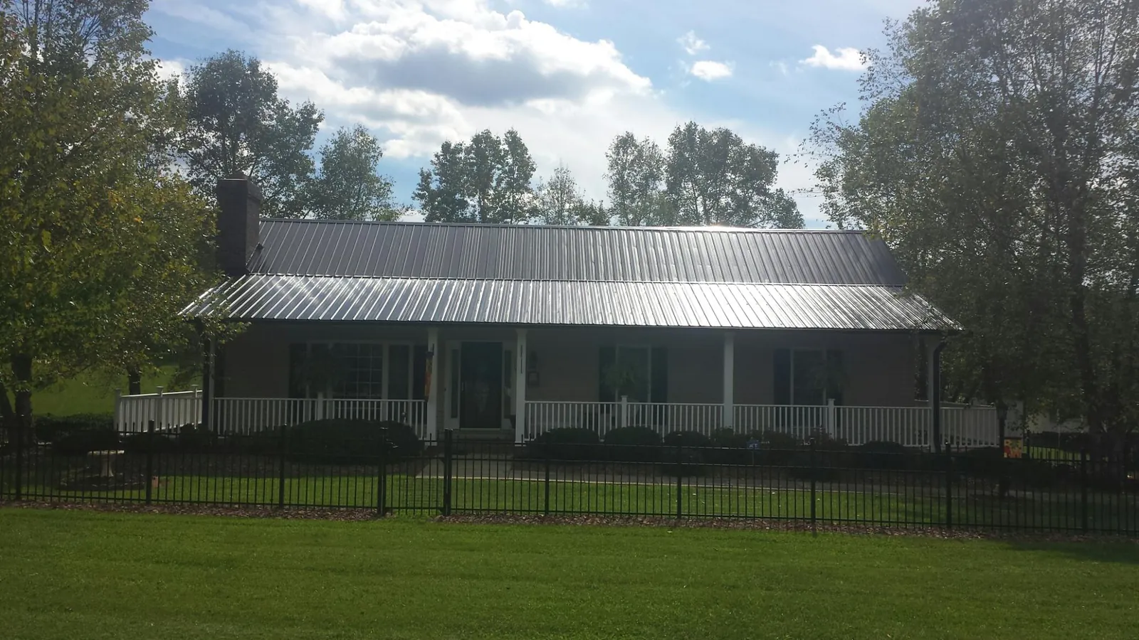 Gray metal roof on a brick ranch with a full width front porch — Gutter Guard Installation work by our crew in Baltic