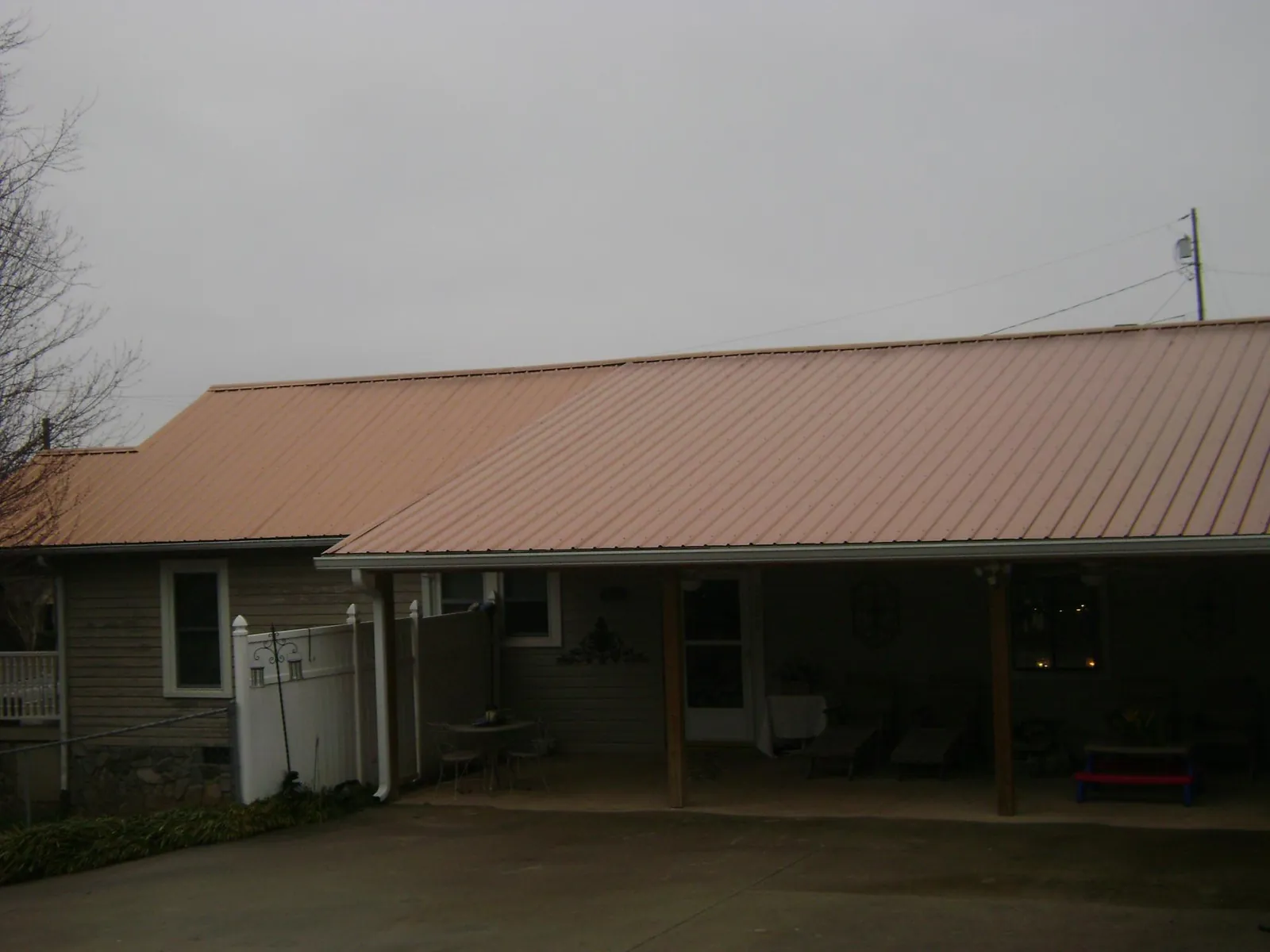 Copper toned metal roof over a wide covered patio in Baltic