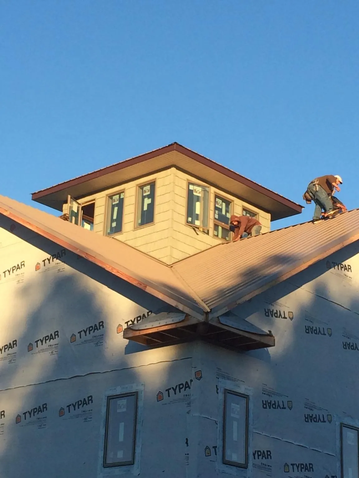 Roofers working around a rooftop cupola on a new metal roof at sunset — Roof Waterproofing in Baltic by Roofing Brothers